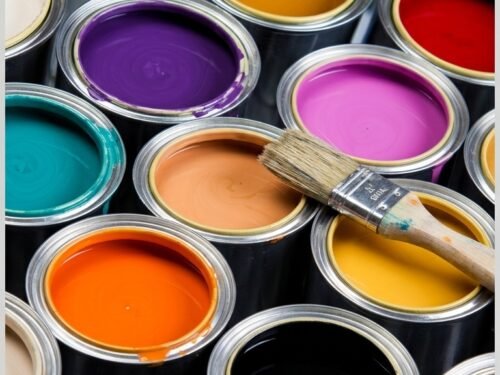 Vista superior de latas abiertas con variados colores de Pinturas Pixel comercializadas por Cemker y una brocha.